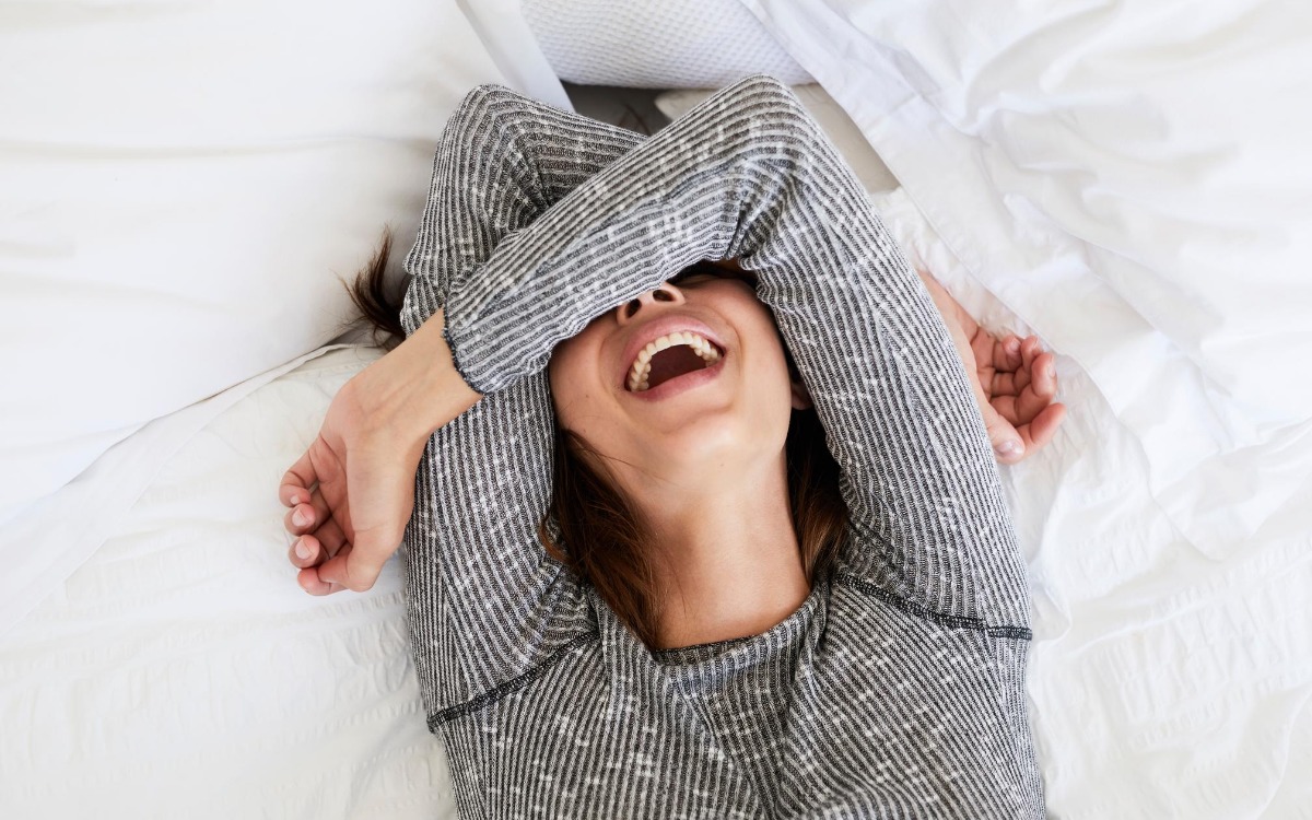 ベッドで笑い転げる女性